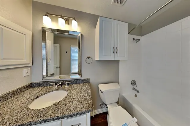 a bathroom with a granite countertop sink mirror vanity and toilet