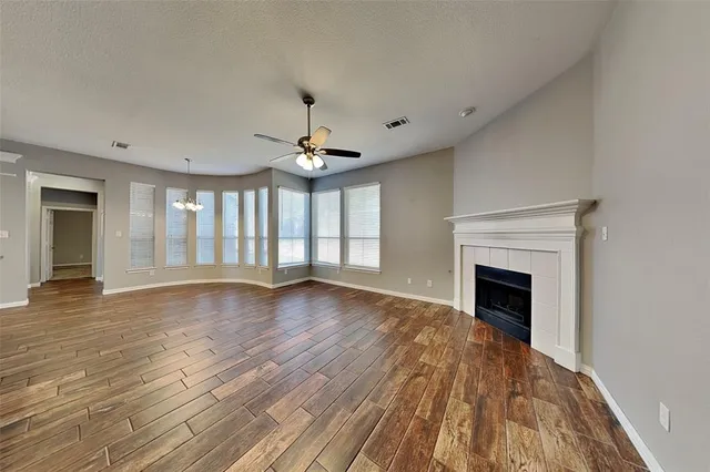 a view of an empty room with wooden floor fireplace and a window