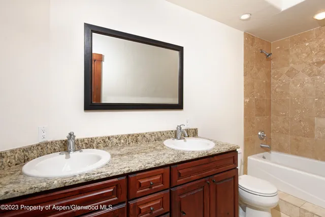 a bathroom with a granite countertop sink toilet a mirror and bathtub