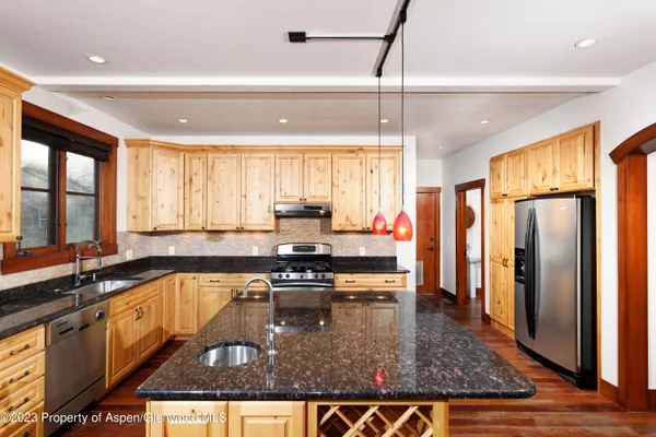 a kitchen with stainless steel appliances granite countertop a refrigerator a sink dishwasher a stove and white cabinets with wooden floor