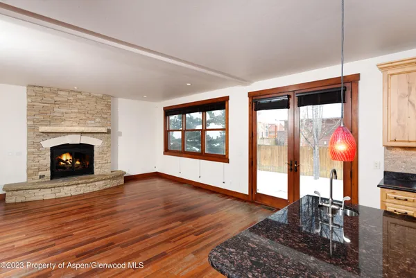 a view of an empty room with wooden floor fireplace and a window
