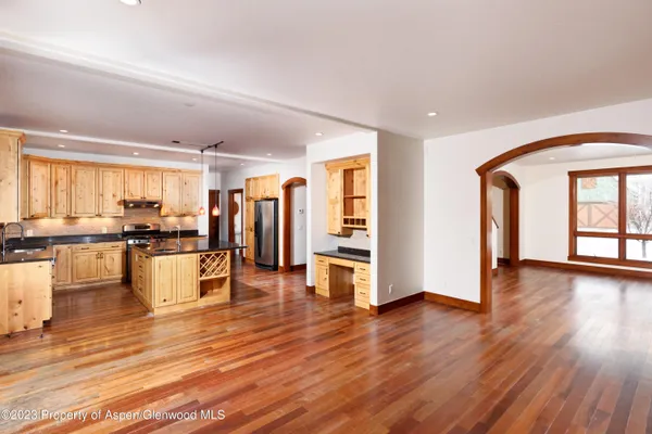 a view of a living room kitchen and kitchen with stove and wooden floor