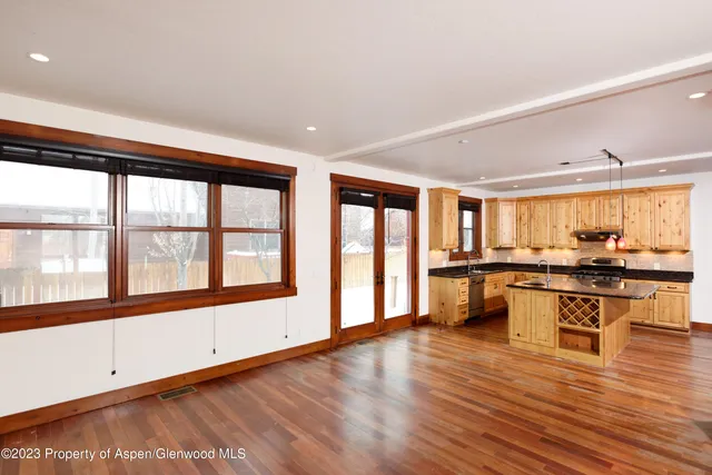 a large white kitchen with stainless steel appliances granite countertop a stove and a large window