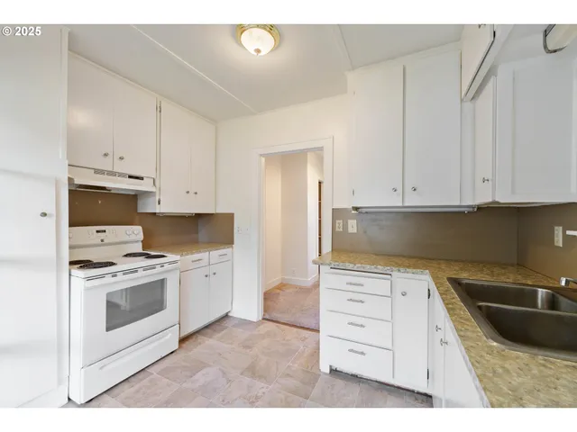 a kitchen with granite countertop a sink a stove and cabinets