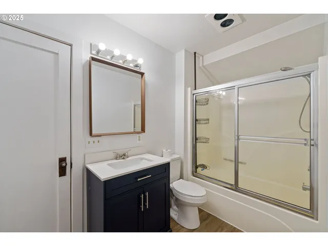 a bathroom with a sink vanity granite toilet and shower