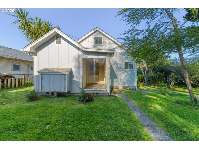 a view of a house with a yard and large trees