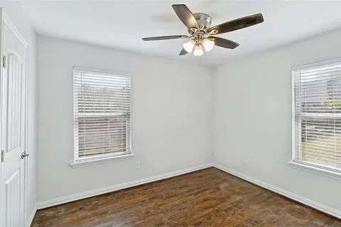 a view of an empty room with window and ceiling fan