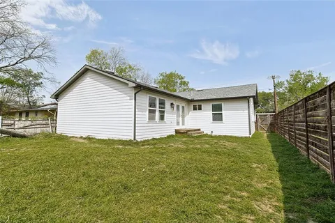 a view of a backyard with plants and large tree
