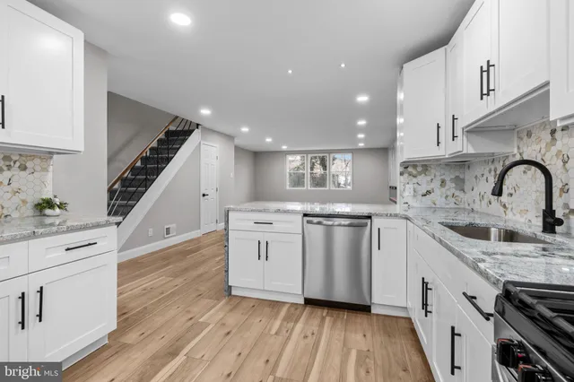 a kitchen with white cabinets stove and sink