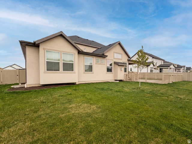 1251 North 2525 West Clinton, UT 84015 - Photo 28 of 30 Expansive green lawn bordering the property, featuring a beige privacy fence and a young deciduous tree