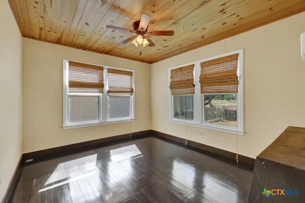 a view of an empty room with a window and wooden floor