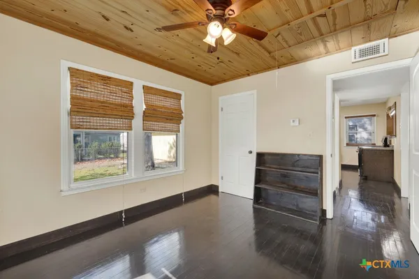 a view of empty room with wooden floor and fan