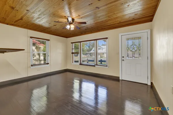 a view of an empty room with wooden floor and a window