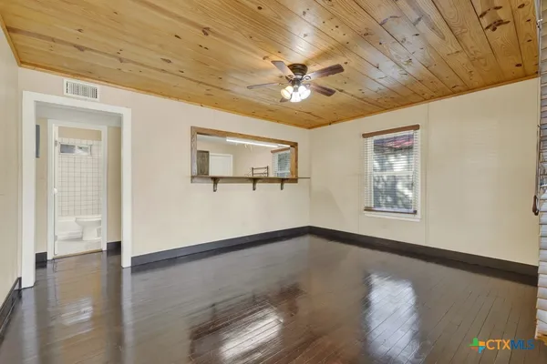 a view of an empty room with a window and wooden floor
