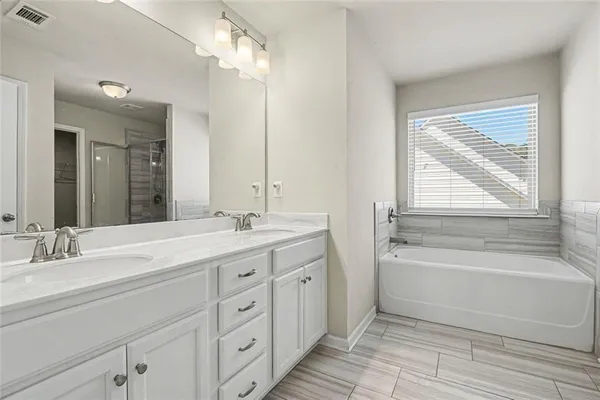 a bathroom with a double vanity sink a large mirror and a bathtub
