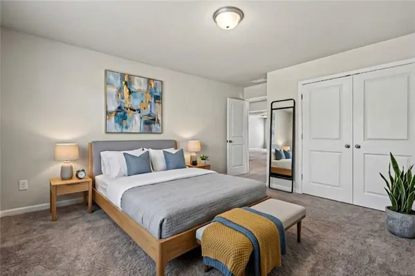 a spacious bedroom with a bed a couch and potted plant on the dresser
