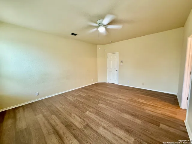 an empty room with a ceiling fan and wooden floor