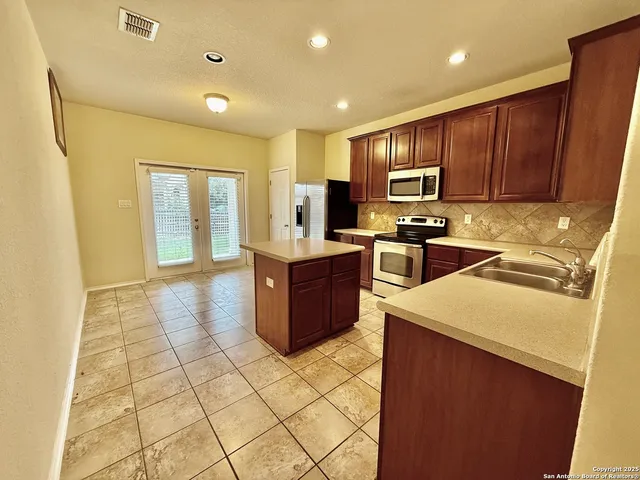 a kitchen with stainless steel appliances granite countertop a sink counter space cabinets and a stove