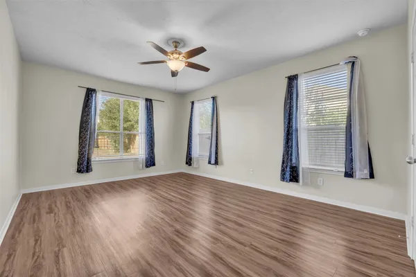 a view of an empty room with a window and wooden floor