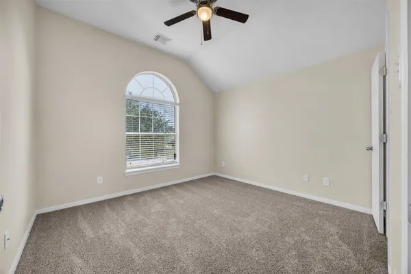 an empty room with ceiling fan and window