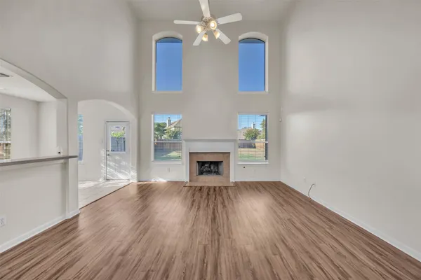 a view of an empty room with wooden floor fireplace and a window
