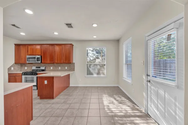 a large kitchen with stainless steel appliances granite countertop a stove a sink and a microwave