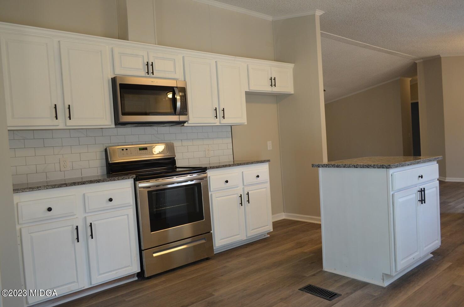 988 Lassiter Road Forsyth, GA 31029 - Photo 5 of 23 a kitchen with white cabinets stainless steel appliances and wooden floor
