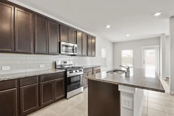 a kitchen with stainless steel appliances granite countertop a sink stove and cabinets