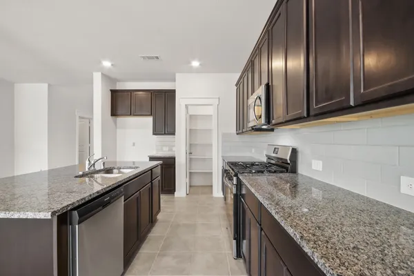 a kitchen with granite countertop stainless steel appliances sink stove microwave and cabinets