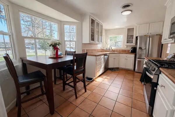 a kitchen with granite countertop a table chairs stove and refrigerator