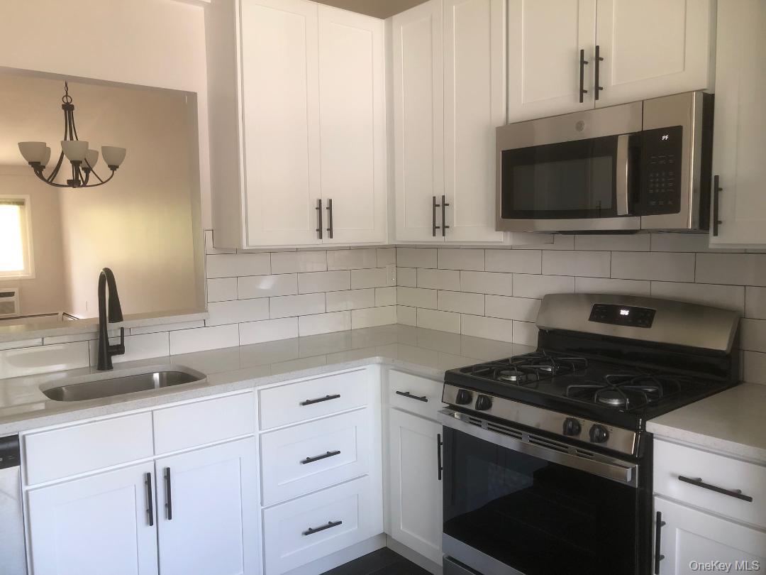 85 North Middletown Road, Unit A7 Nanuet, NY 10954 - Photo 3 of 12 Beautifully just renovated eat in kitchen featuring lots white shaker cabinetry with dark hardware, quartz counters, stainless steel appliances, subway tile backsplash, and pretty tile floor.