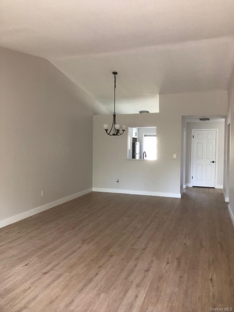 85 North Middletown Road, Unit A7 Nanuet, NY 10954 - Photo 6 of 12 Spacious, open living/dining room featuring vaulted ceilings, a contemporary chandelier, and wood-like flooring