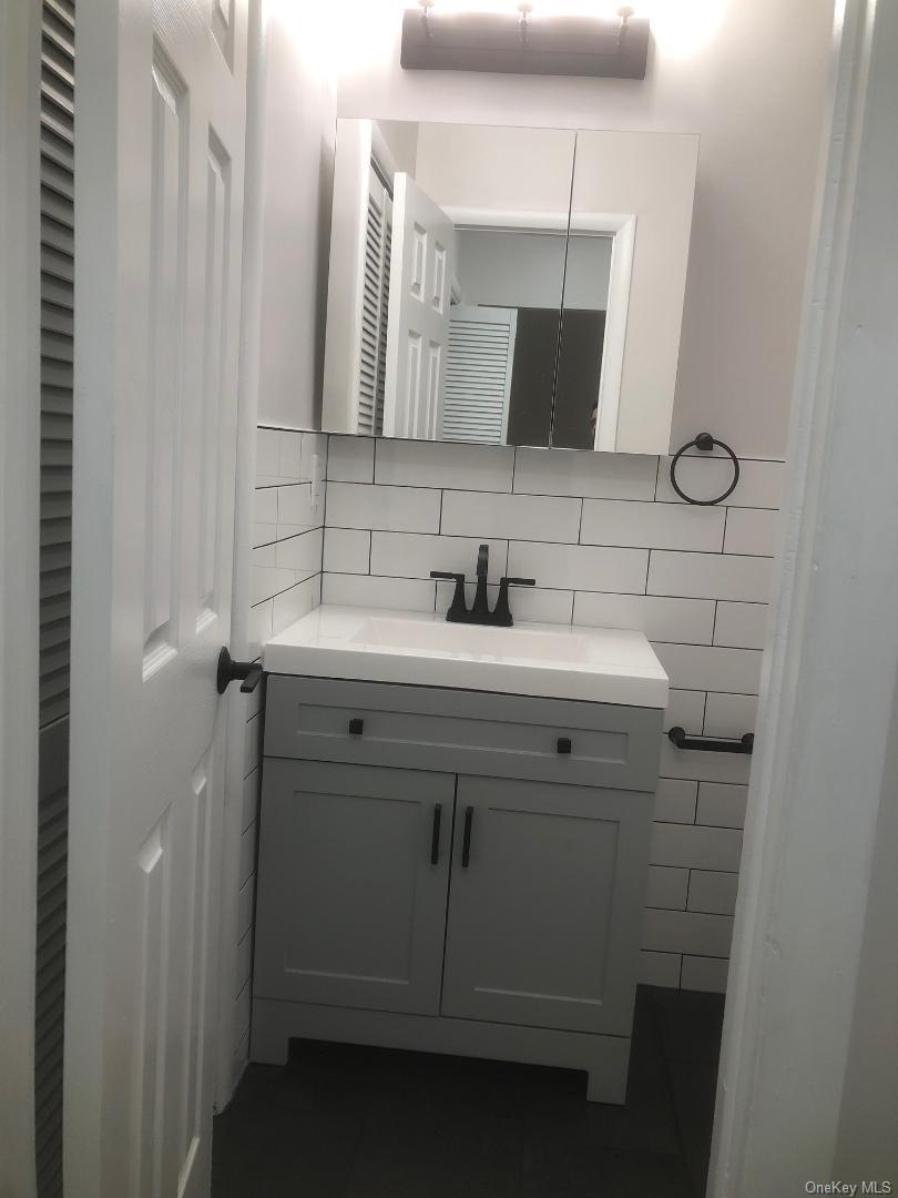 85 North Middletown Road, Unit A7 Nanuet, NY 10954 - Photo 9 of 12 Pretty updated bathroom which features a vanity featuring a light gray shaker-style cabinet, integrated sink, and matte black hardware