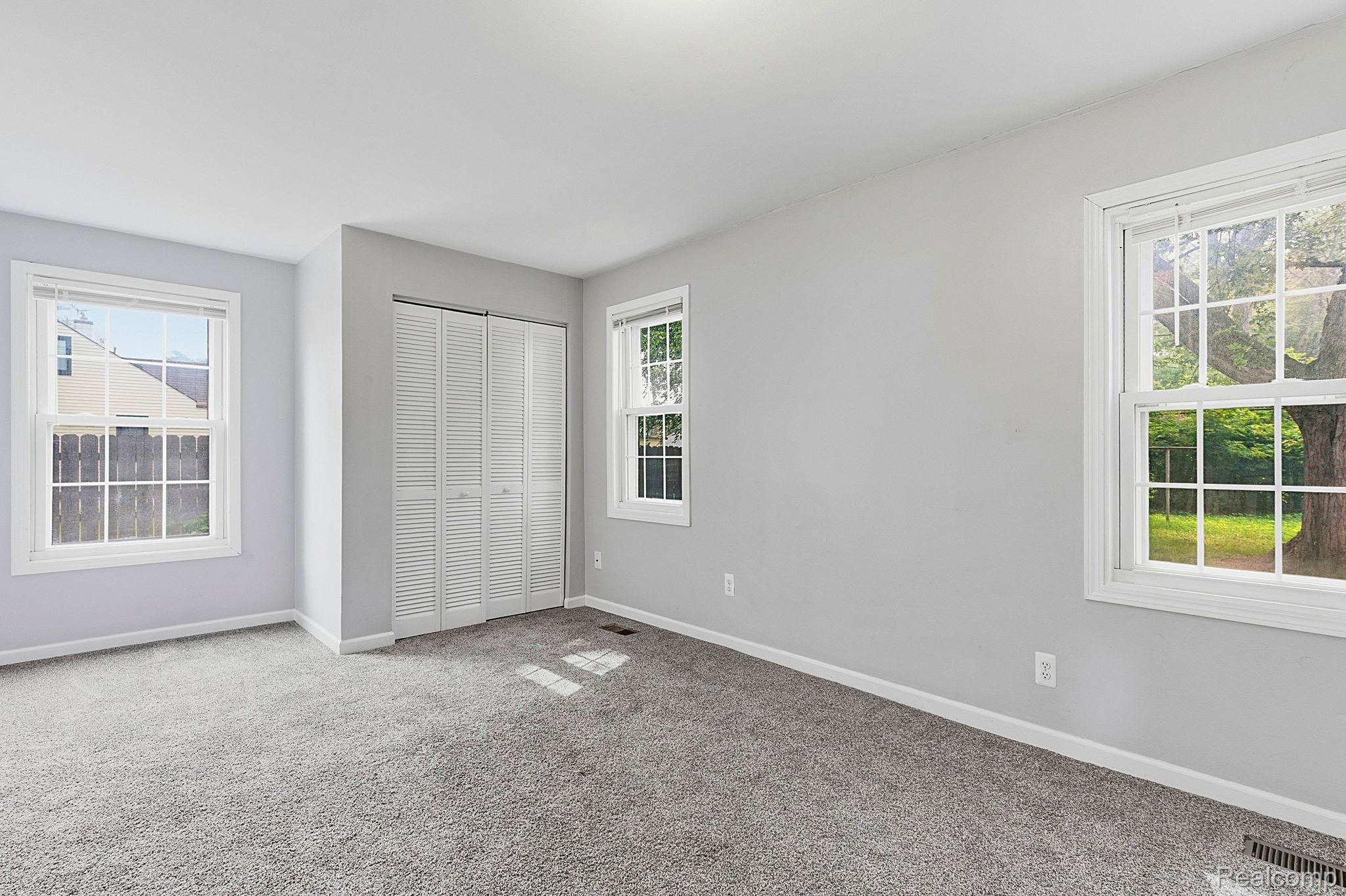5852 Beech Daly Road Taylor, MI 48180 - Photo 10 of 29 Spacious room featuring light gray walls, plush gray carpeting, white trim, and multiple double-hung windows