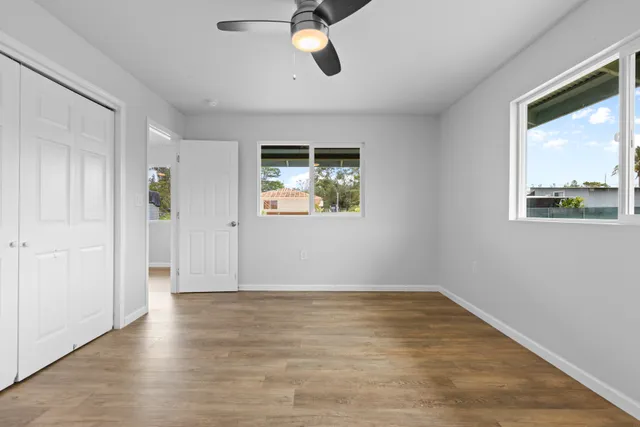 an empty room with wooden floor cabinet and windows