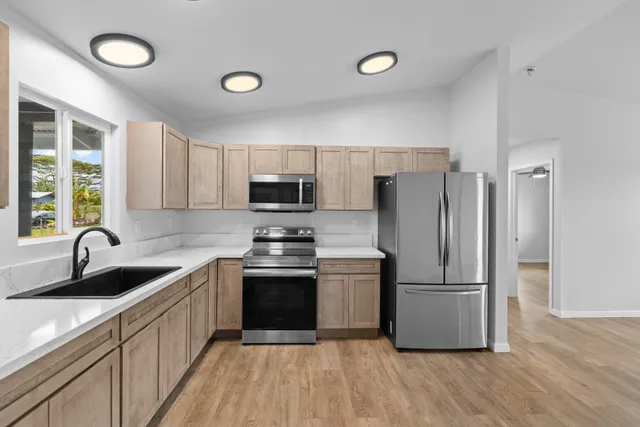 a kitchen with kitchen island granite countertop a sink stainless steel appliances and cabinets