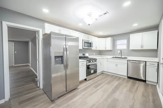 a kitchen with granite countertop white cabinets and stainless steel appliances