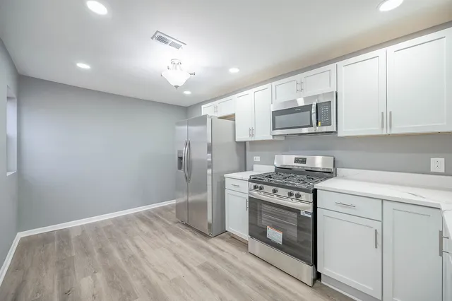 a kitchen with granite countertop a stove a sink and a refrigerator