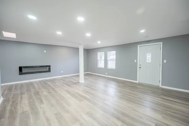 a view of an empty room with wooden floor and windows