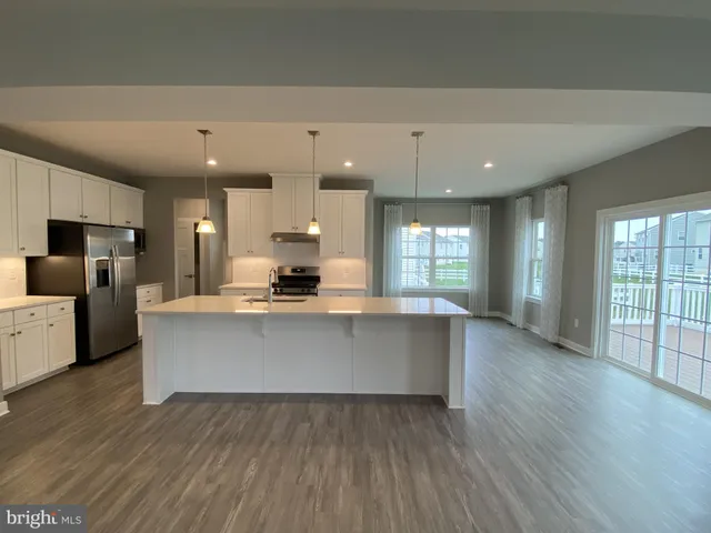 a large kitchen with stainless steel appliances a large counter top a stove and a refrigerator