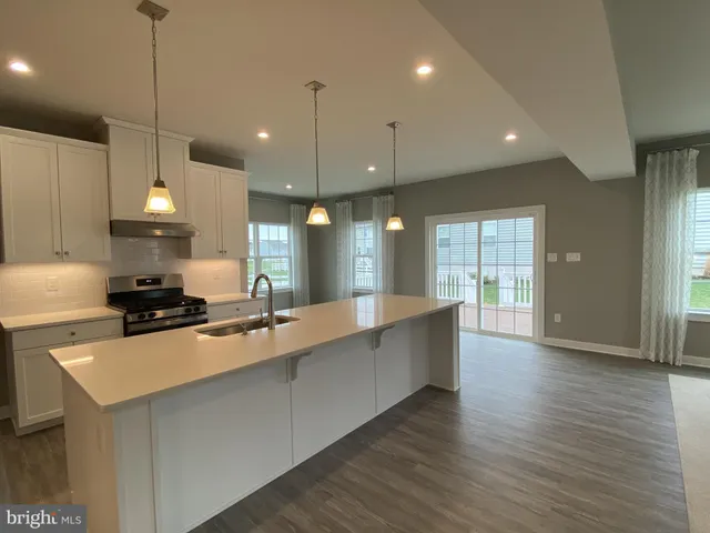 a large kitchen with stainless steel appliances granite countertop a stove a sink a center island and a wooden floor