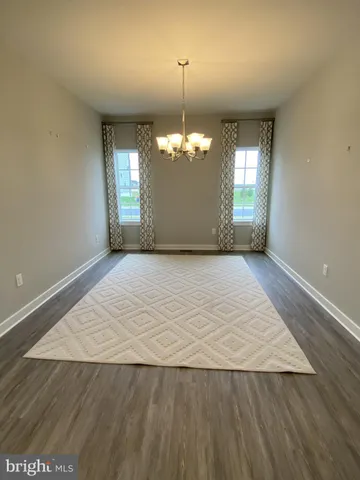 an empty room with wooden floor chandelier and windows