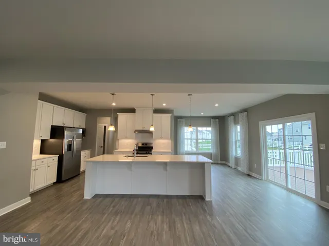 a large living room with stainless steel appliances kitchen island granite countertop a large window and a couch