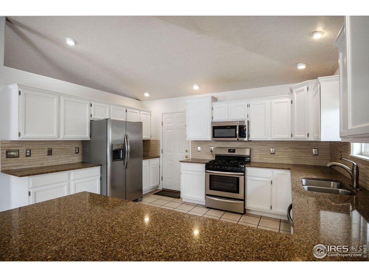 1743 68th Avenue Greeley, CO 80634 - Photo 6 of 30 a kitchen with a refrigerator and a stove top oven