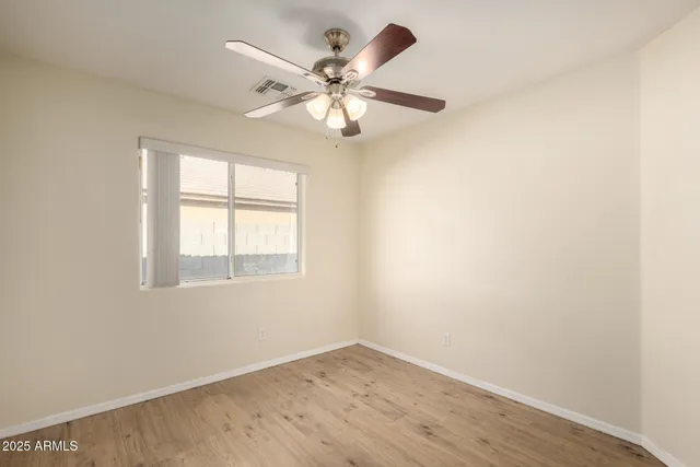 an empty room with wooden floor fan and windows