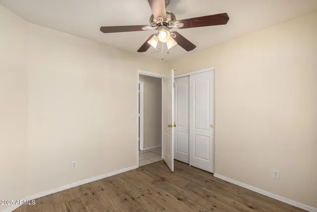 an empty room with wooden floor fan and windows