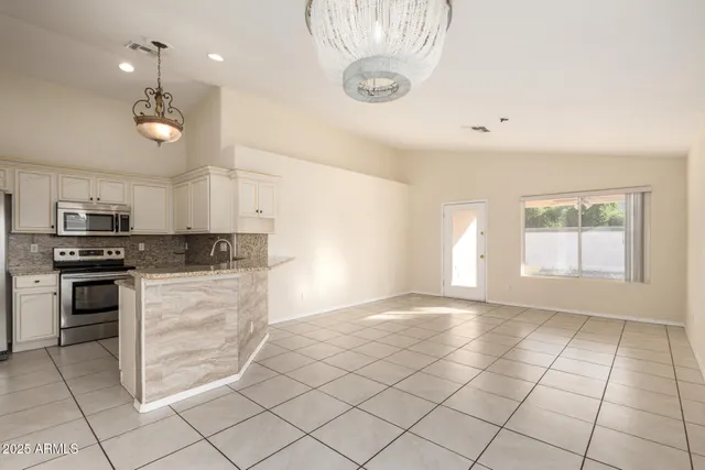 a kitchen with granite countertop a stove a sink and a refrigerator