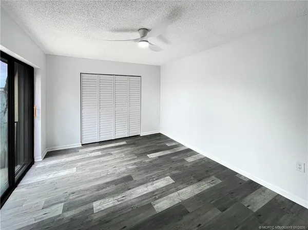 an empty room with wooden floor and bathroom view