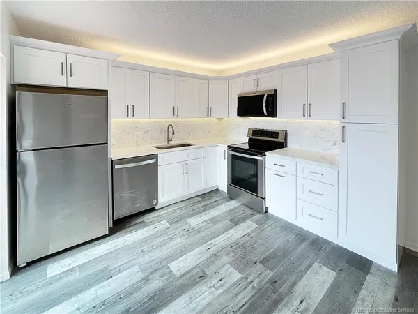 a kitchen with cabinets stainless steel appliances and wooden floor