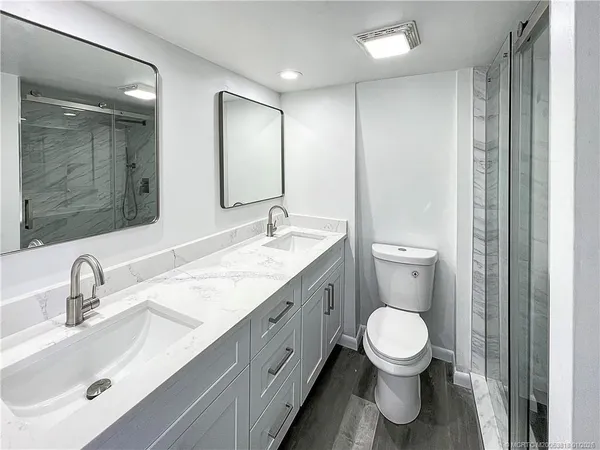 a bathroom with a sink a toilet a mirror and shower